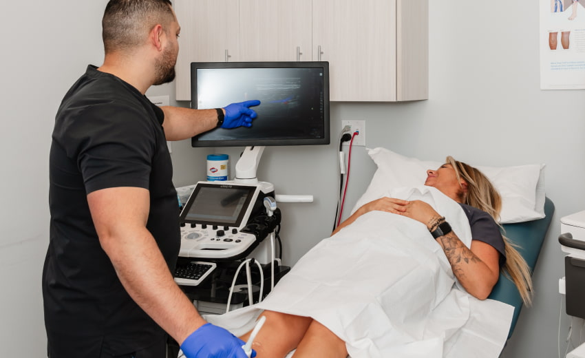 a photo of a technician administering vascular ultrasound to the calf of a patient