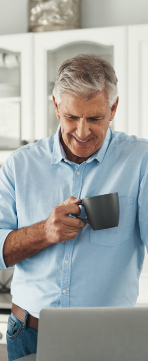 a photo of a person happily drinking a cup of coffee while working on their laptop