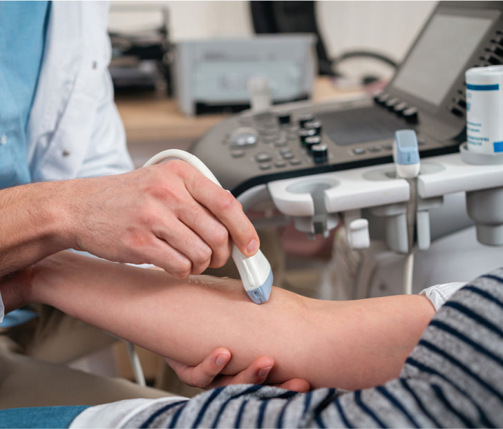 a photo of a technician administering vascular ultrasound to the forearm of a patient